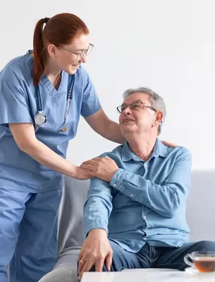 Nurse checking senior man’s blood pressure while seated at kitchen table