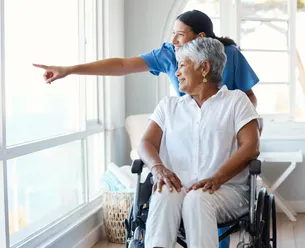 Home health aide preparing medication organizer on countertop in residential kitchen